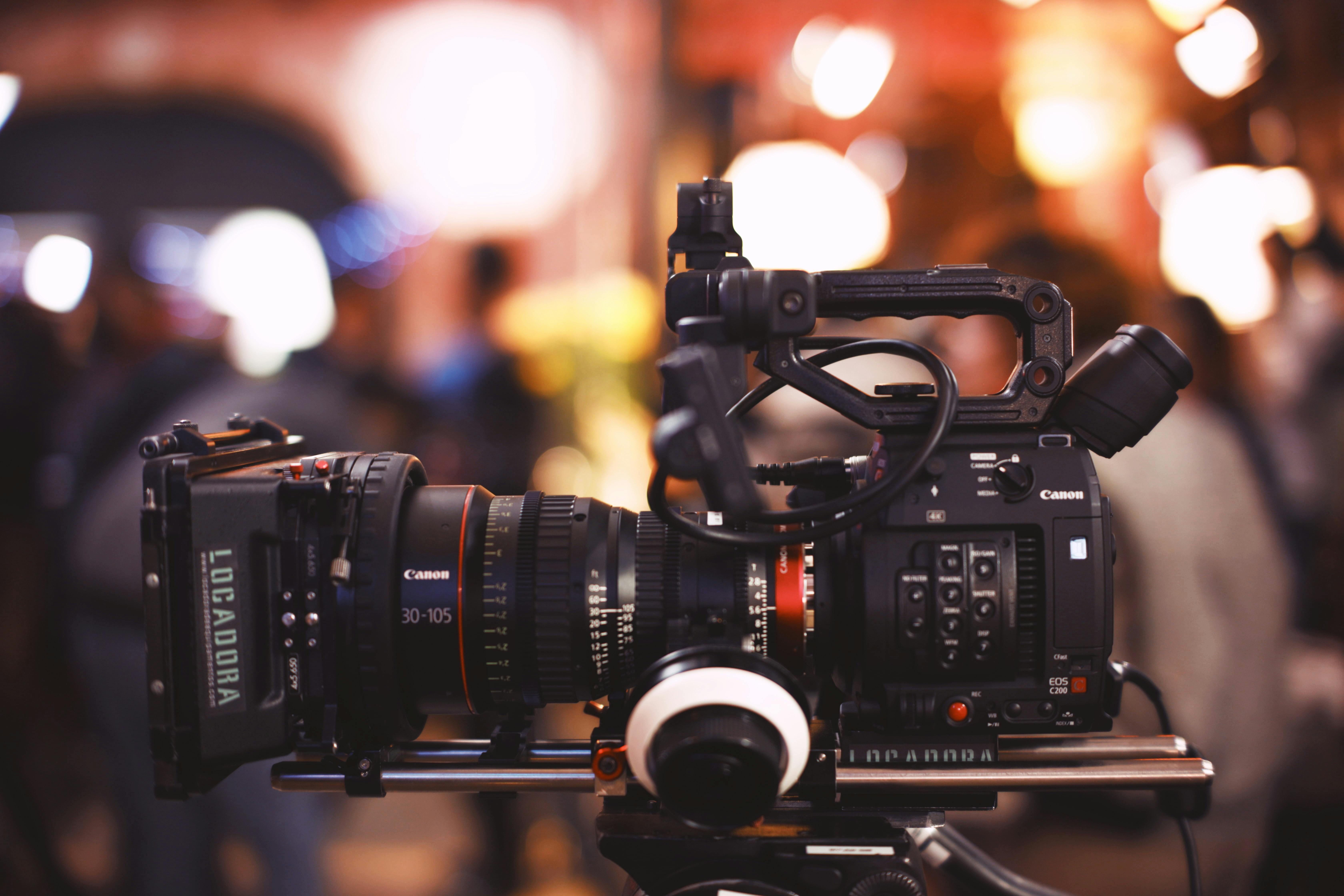 Close-up of a Canon video camera with a blurred bokeh background, ideal for filmmaking stock.