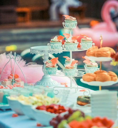 A beautifully arranged dessert table at an outdoor summer party near a pool.