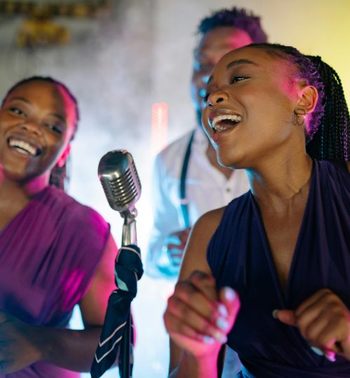 Energetic live performance by African American singers with vintage microphone, vibrant lighting.